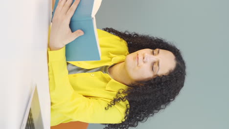 Vertical-video-of-Young-woman-with-notebook-thinks-and-takes-notes.